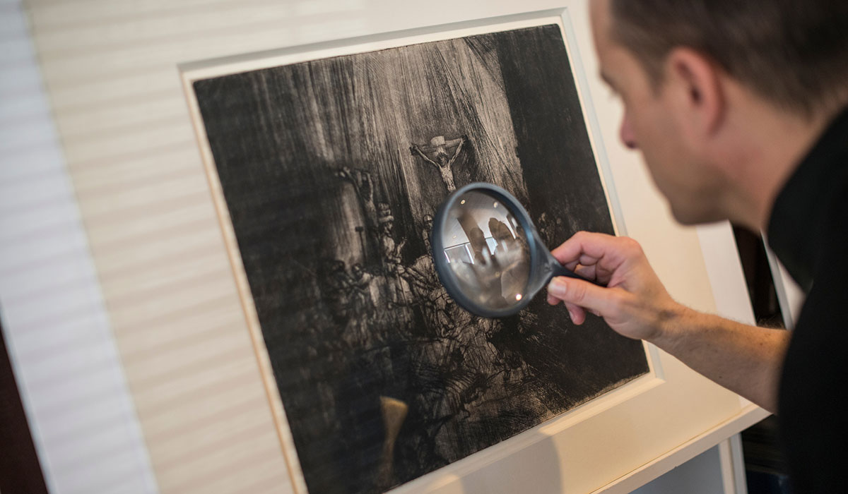 Student studying piece of art with magnifying glass