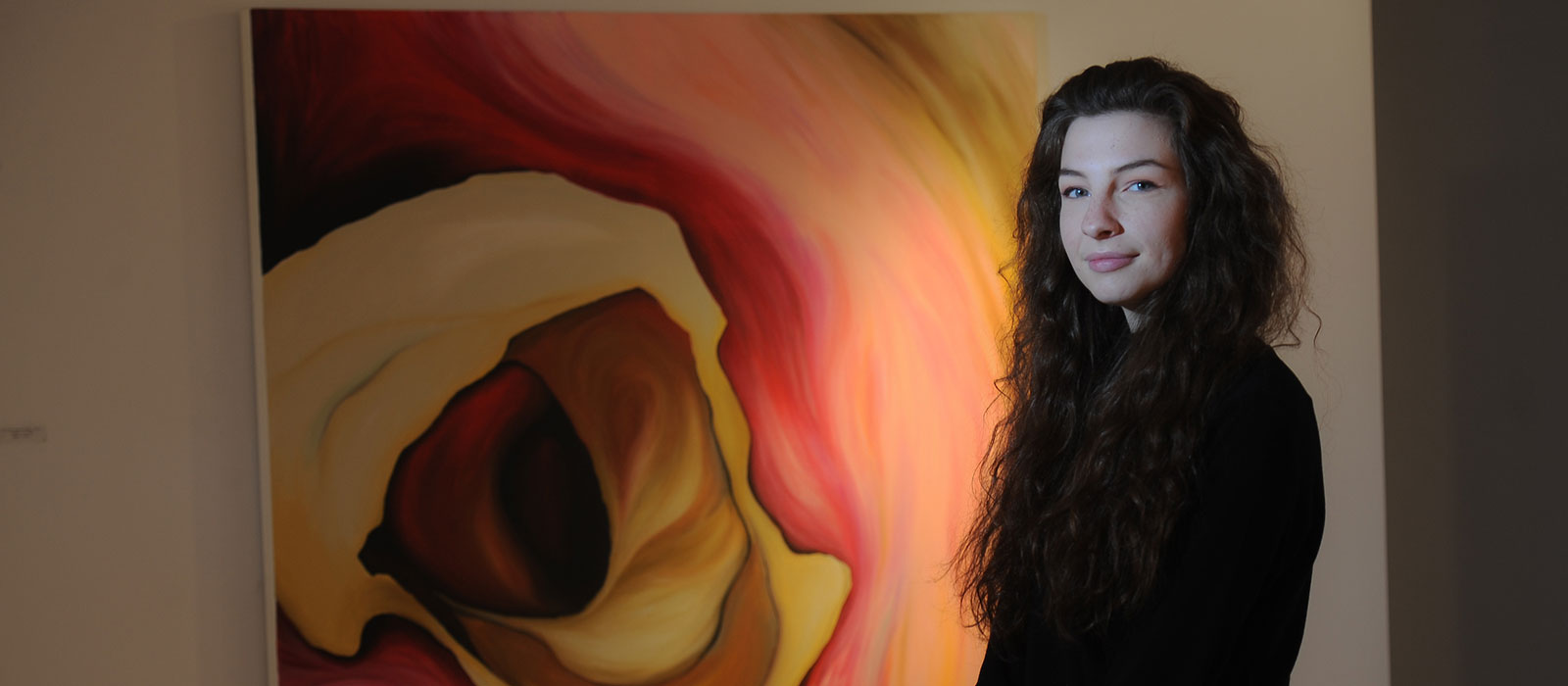 Art alumna in front of her artwork 