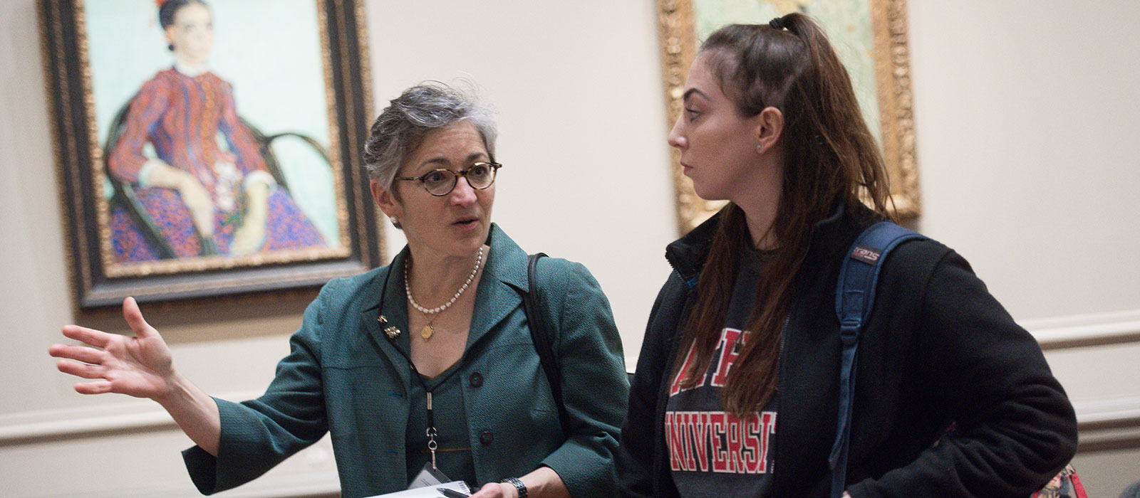 Professor talking to student in art museum